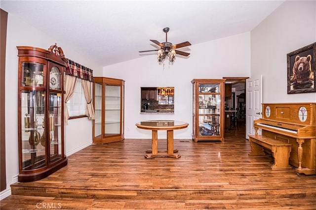 misc room with ceiling fan, wood-type flooring, and vaulted ceiling