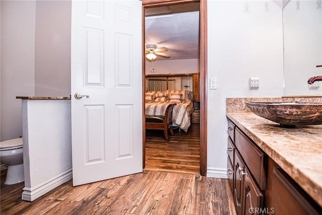 bathroom featuring breakfast area, vanity, ceiling fan, hardwood / wood-style flooring, and toilet