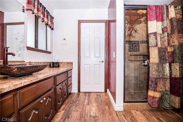 bathroom with a tile shower, vanity, and hardwood / wood-style flooring