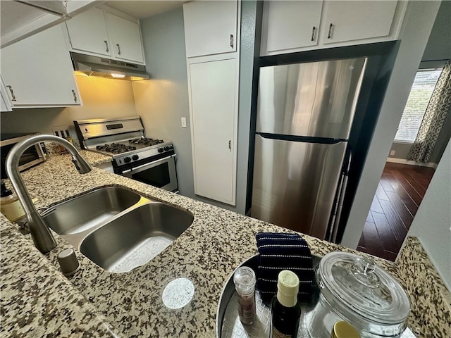 kitchen featuring light stone counters, white cabinets, sink, hardwood / wood-style flooring, and appliances with stainless steel finishes