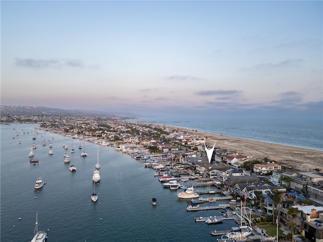 aerial view at dusk with a water view and a view of the beach