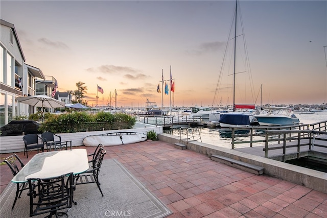 patio terrace at dusk featuring a water view