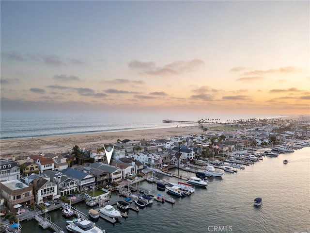 aerial view at dusk featuring a view of the beach and a water view