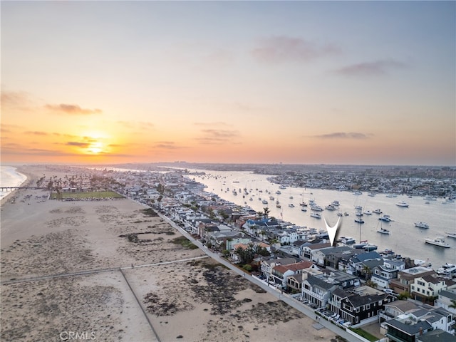 aerial view at dusk with a water view and a beach view