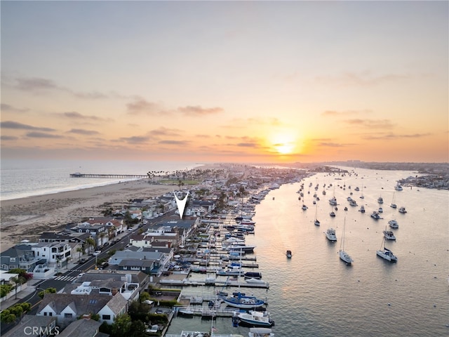 aerial view at dusk with a view of the beach and a water view