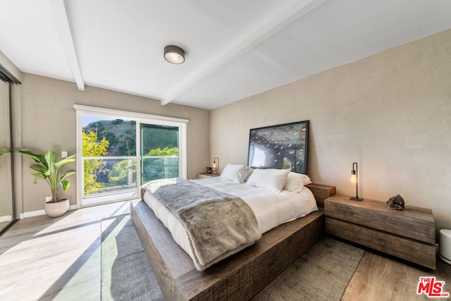 bedroom featuring light hardwood / wood-style floors and beamed ceiling