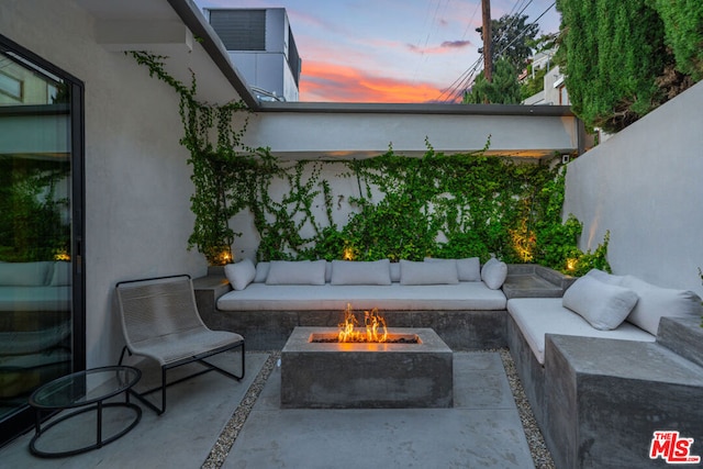 patio terrace at dusk featuring an outdoor living space with a fire pit