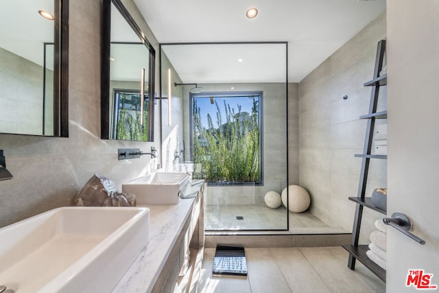 bathroom featuring walk in shower, vanity, and tile walls