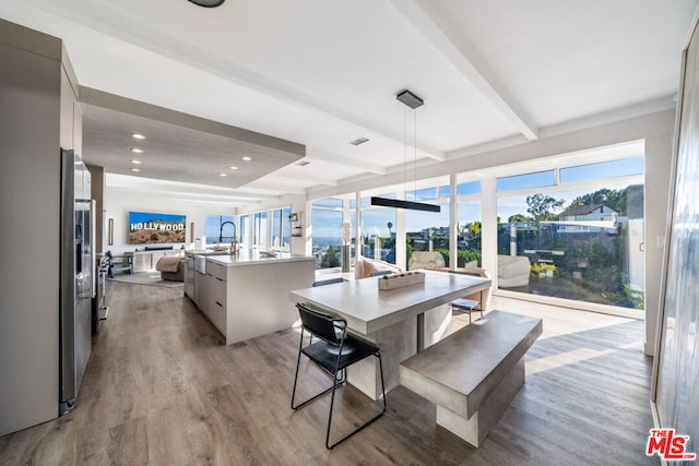 dining space featuring light hardwood / wood-style floors, beamed ceiling, and plenty of natural light