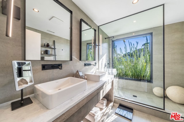 bathroom featuring walk in shower, vanity, tile walls, and tile patterned floors