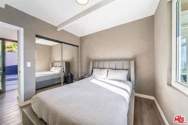 bedroom featuring vaulted ceiling with beams, hardwood / wood-style floors, and a closet