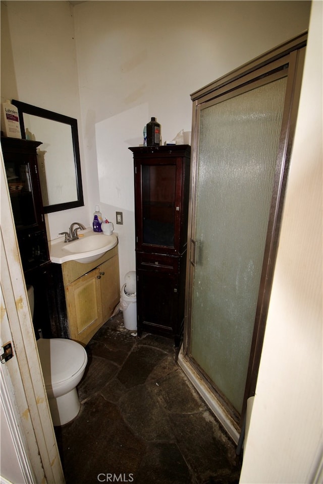 bathroom featuring vanity, a shower with shower door, and toilet