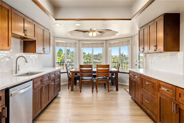 kitchen with sink, a tray ceiling, stainless steel dishwasher, and a healthy amount of sunlight