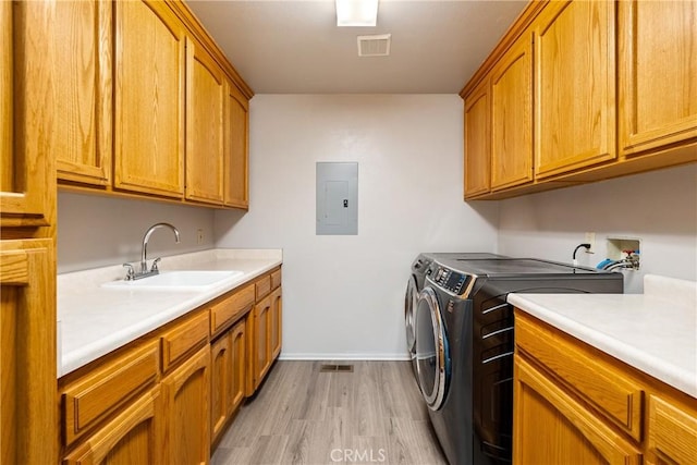 laundry area with separate washer and dryer, sink, cabinets, electric panel, and light hardwood / wood-style floors