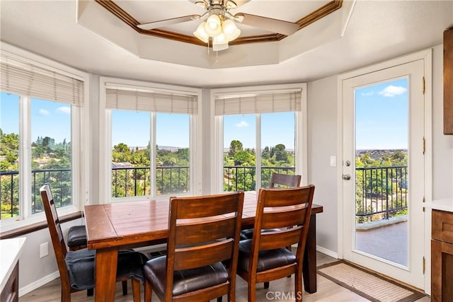 sunroom featuring a raised ceiling and ceiling fan