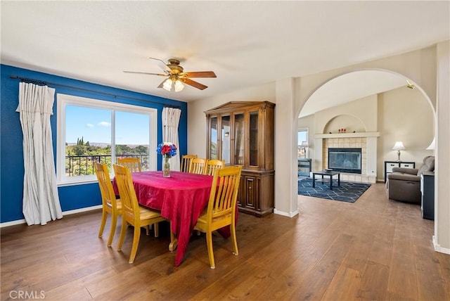 dining area with a tiled fireplace, dark hardwood / wood-style floors, and ceiling fan