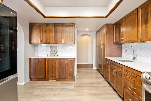 kitchen with sink, stainless steel range, light hardwood / wood-style floors, and decorative backsplash