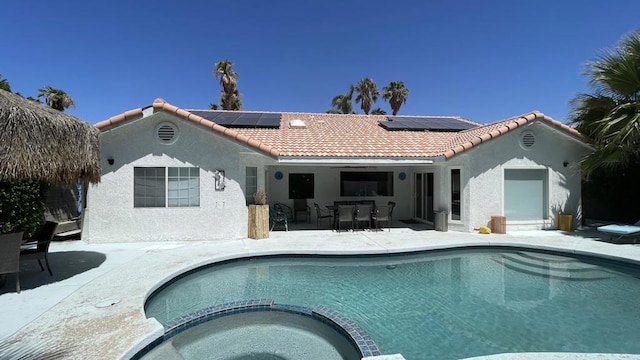 rear view of house featuring a patio, a pool with hot tub, and solar panels