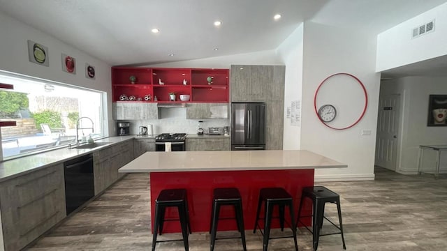 kitchen with lofted ceiling, a breakfast bar area, sink, a center island, and appliances with stainless steel finishes