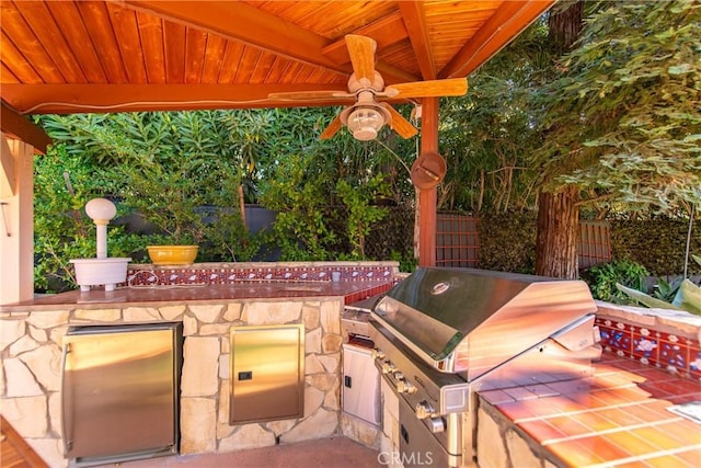 view of patio featuring ceiling fan, area for grilling, and exterior kitchen