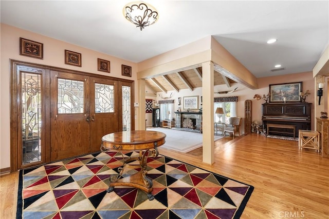 foyer entrance with wood-type flooring and vaulted ceiling with beams