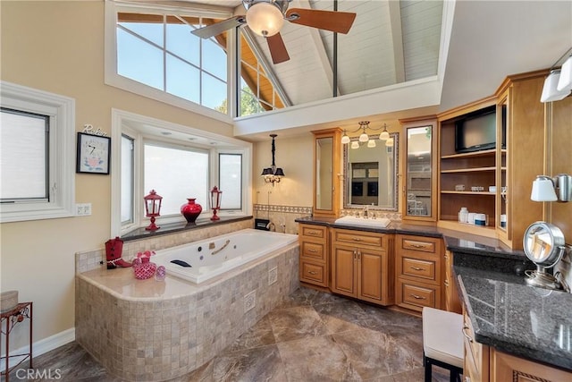 bathroom featuring tiled bath, beamed ceiling, vanity, and a towering ceiling