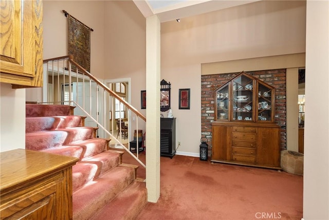 stairway featuring a high ceiling and carpet flooring