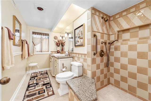 bathroom featuring toilet, tile patterned flooring, tiled shower, and vanity