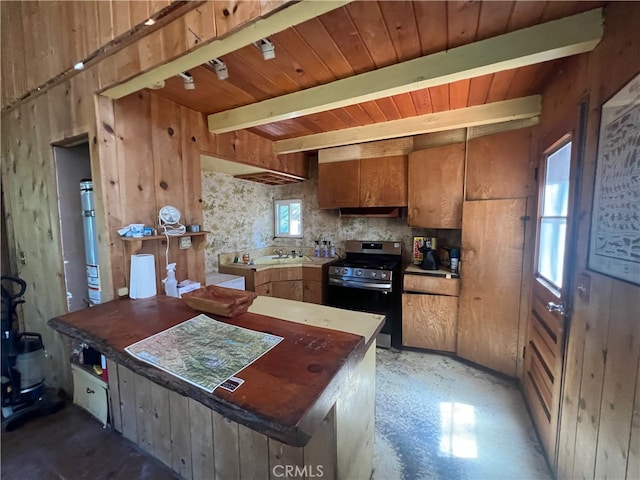 kitchen with beamed ceiling, wooden walls, gas stove, and sink