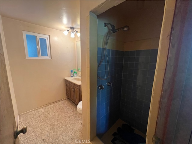 bathroom featuring vanity, tiled shower, toilet, and ceiling fan