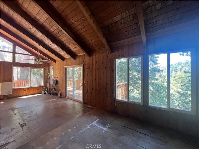 spare room featuring plenty of natural light, ceiling fan, lofted ceiling with beams, and wooden walls