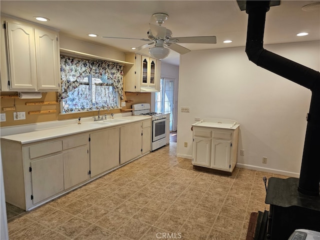 kitchen with ceiling fan, white gas stove, a wood stove, and sink