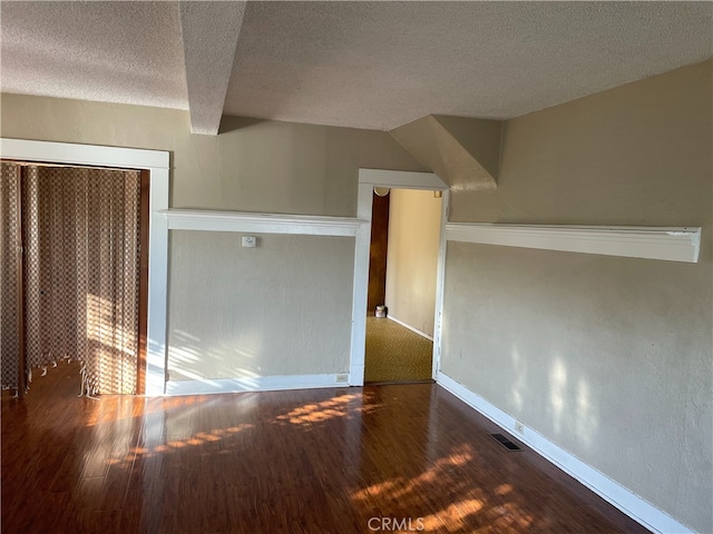 interior space with a textured ceiling and dark hardwood / wood-style flooring