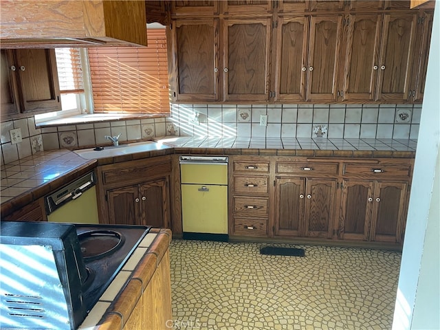 kitchen with decorative backsplash, sink, tile patterned floors, white dishwasher, and tile counters