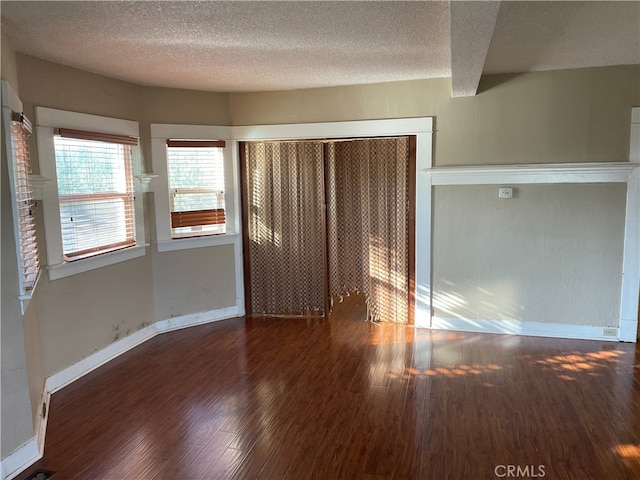 unfurnished bedroom featuring dark wood-type flooring, a closet, and a textured ceiling