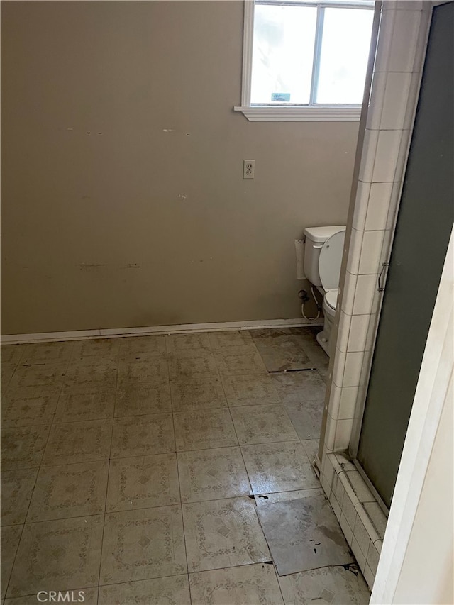 bathroom featuring a shower with door and toilet