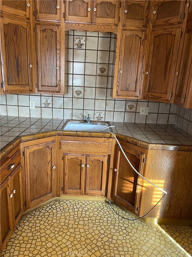 kitchen featuring light tile patterned floors, tile countertops, sink, and decorative backsplash