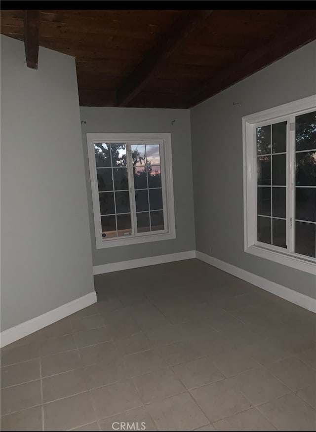 tiled empty room featuring lofted ceiling with beams and wood ceiling