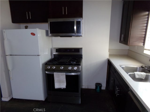 kitchen featuring stainless steel appliances, dark brown cabinets, sink, and dark tile patterned floors