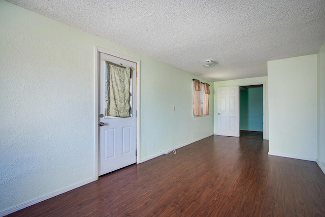 empty room featuring a textured ceiling and dark wood-type flooring