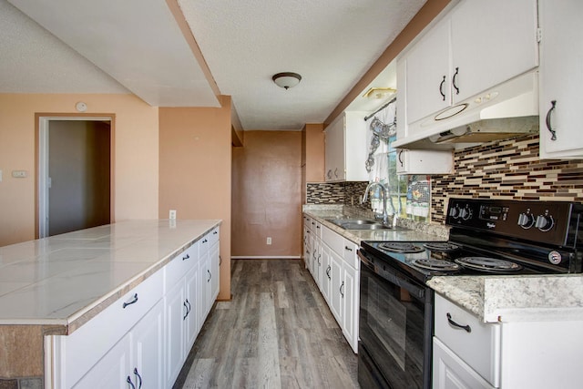 kitchen with light hardwood / wood-style flooring, black range with electric cooktop, sink, white cabinets, and tasteful backsplash