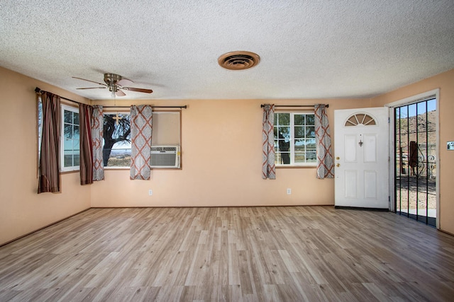 foyer with a healthy amount of sunlight, a textured ceiling, and light wood-type flooring