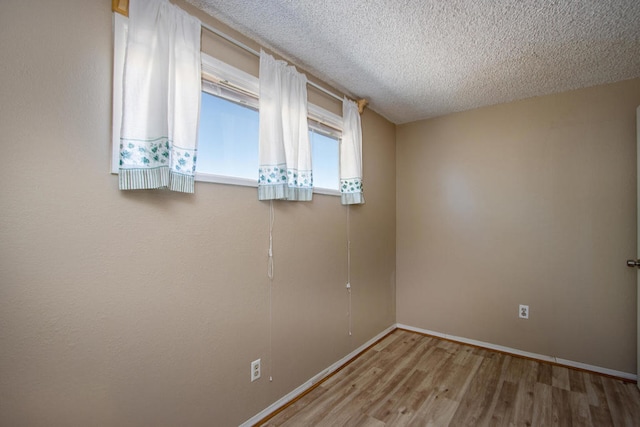 empty room with wood-type flooring and a textured ceiling