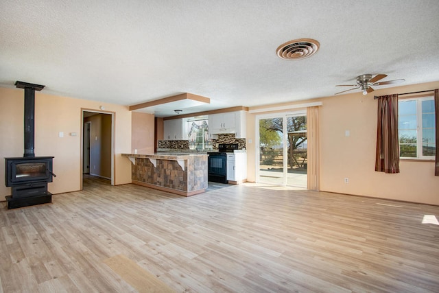 unfurnished living room with a wealth of natural light, a textured ceiling, light wood-type flooring, and ceiling fan