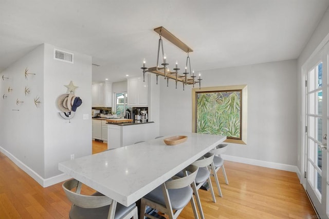 dining space with light hardwood / wood-style floors and a chandelier