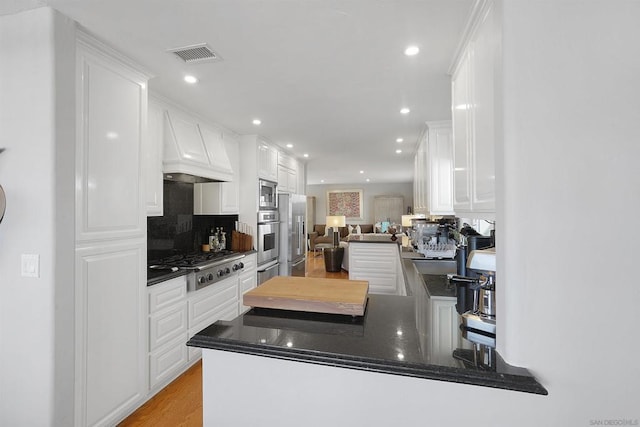 kitchen featuring white cabinets, appliances with stainless steel finishes, backsplash, and kitchen peninsula