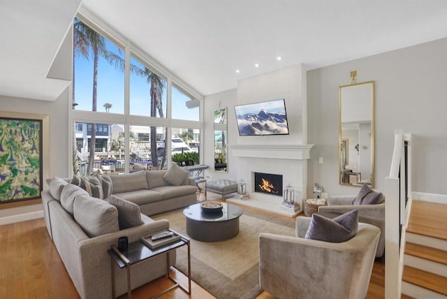 living room with a large fireplace, high vaulted ceiling, and hardwood / wood-style flooring