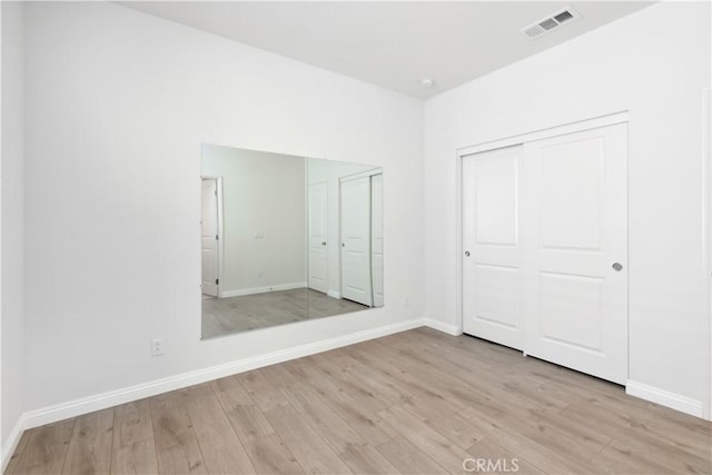 unfurnished bedroom with light hardwood / wood-style flooring and a closet