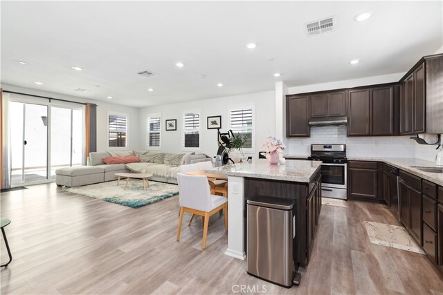 kitchen with stainless steel range, light hardwood / wood-style flooring, dark brown cabinets, light stone counters, and a center island