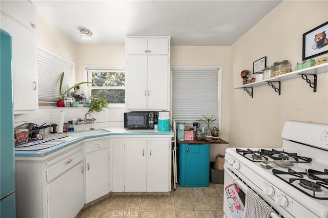 kitchen with white cabinets, decorative backsplash, sink, and white range with gas cooktop